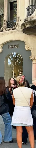 Personas en una calle de Barcelona, frente a la fachada de una tienda Loewe con detalles arquitectónicos ornamentados, bal...