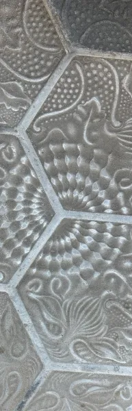 Primer plano de una baldosa hexagonal decorativa gris con patrones orgánicos, escamas y puntos.