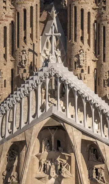 Nahaufnahme der Passionsfassade der Sagrada Família mit geometrischen Formen, vertikalen Türmen und religiösen Skulpturen.