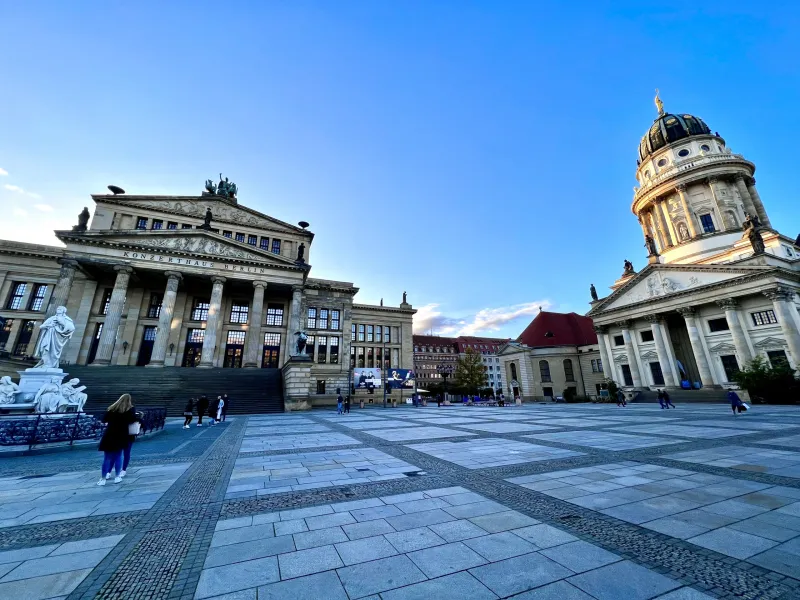 Vista de Gendarmenmarkt en Berlín con el Konzerthaus (izquierda) y el Deutscher Dom (derecha) bajo un cielo azul claro.