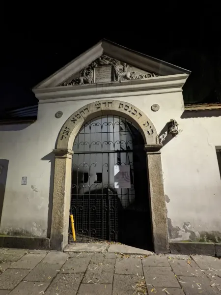 Steinerner Eingang zur Isaak-Synagoge im Krakauer Stadtteil Kazimierz bei Nacht, mit hebräischer Schrift über einem Torbogen.