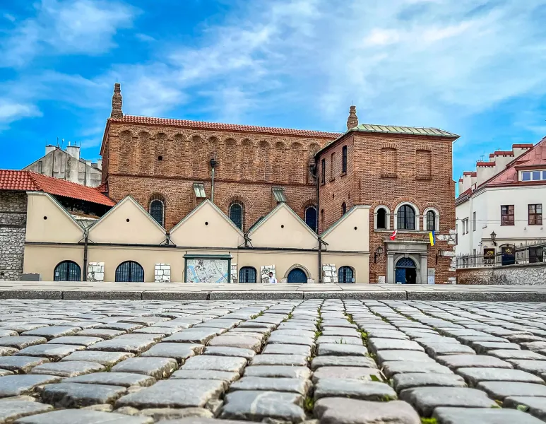 Low angle view of the historic Old Synagogue in Kazimierz, Krakow, with focus on cobblestone foreground.