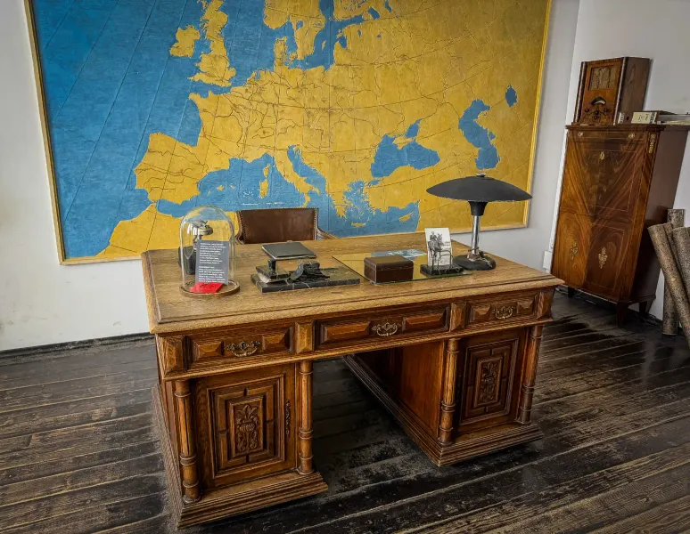 A meticulously recreated office space with a large wooden desk and a vintage map of Europe on the wall, evoking the atmosp...