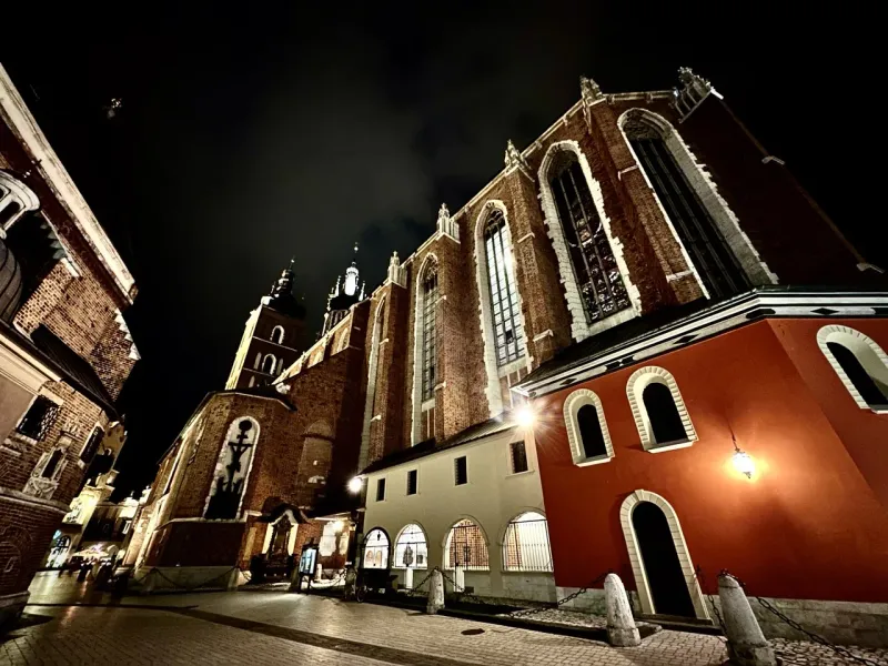 Low-angle view of St. Mary's Basilica in Krakow, illuminated against the dark night sky.