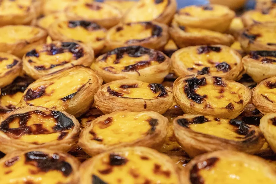 Eine Nahaufnahme von vielen Pastéis de Nata, portugiesischen Puddingtörtchen mit einer dunklen, karamellisierten Oberseite.