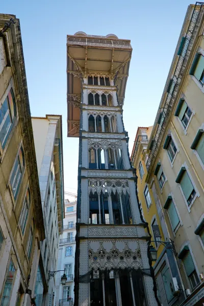 The neo-Gothic Santa Justa Lift, an iron elevator in Lisbon, viewed from street level between buildings.