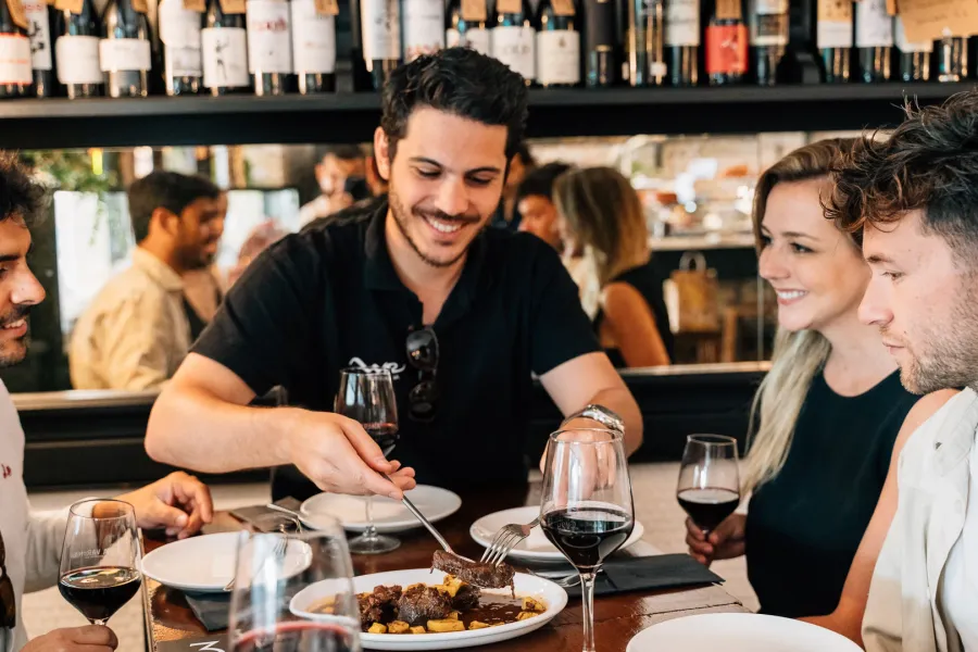 Un grupo de amigos comparte comida y vino tinto en la mesa de un bar de tapas de Madrid.
