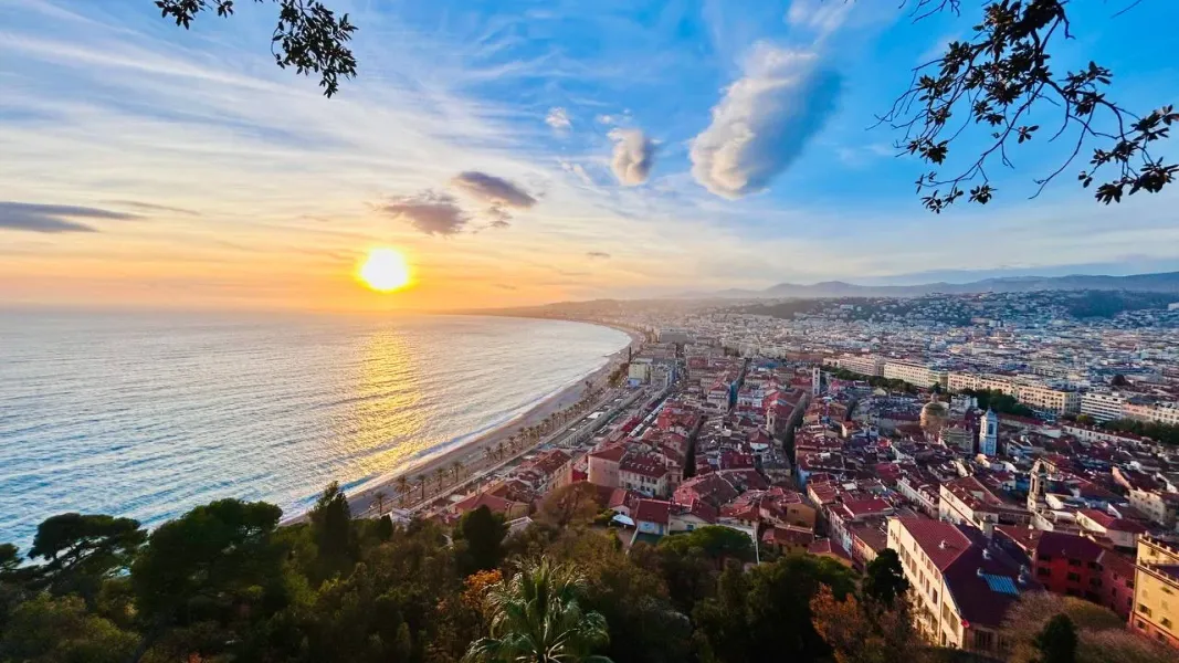 Aerial view of Nice coastline at sunset, with the Promenade des Anglais, Mediterranean Sea, and city buildings under an or...