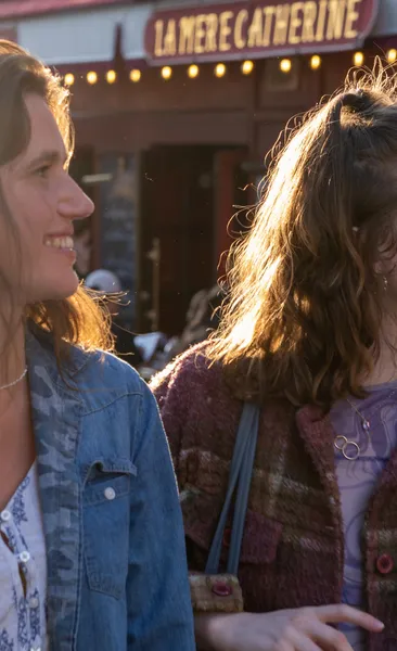 Two people with sunlit hair in front of La Mère Catherine restaurant in Montmartre, Paris.