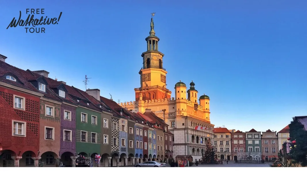 Altes Rathaus von Posen mit hohem Uhrturm, umgeben von farbenfrohen historischen Kaufmannshäusern unter klarem Himmel.