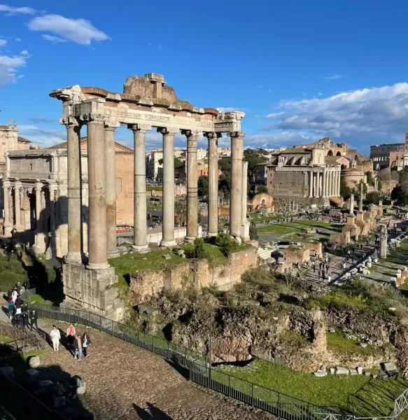 Vista del Foro Romano en Roma, mostrando ruinas antiguas, incluyendo ocho altas columnas del Templo de Saturno bajo un cie...