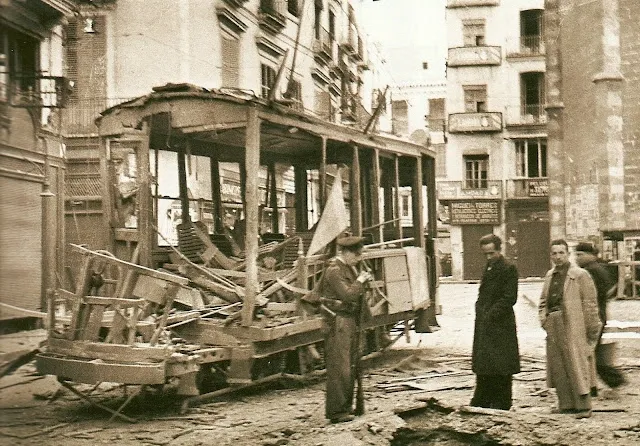 A destroyed tram on a street in Valencia during the Spanish Civil War. Sepia-toned photograph.