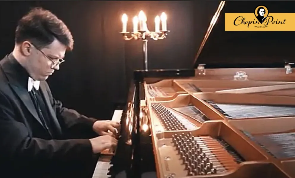 Woman in a green dress sitting at a grand piano in an empty concert hall.