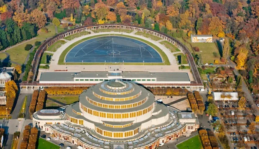Aerial view of Centennial Hall in Wroclaw with its circular tiered roof, surrounded by the semicircular Pergola and autumn...