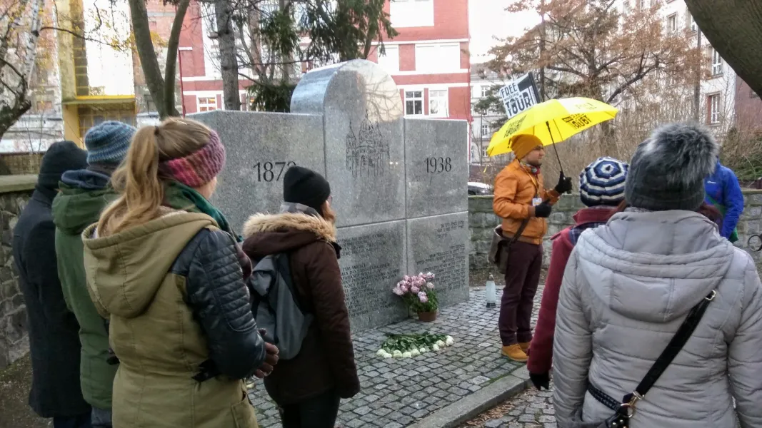 A guided walking tour group in Wrocław, Poland, listens attentively to their guide at a historical monument.