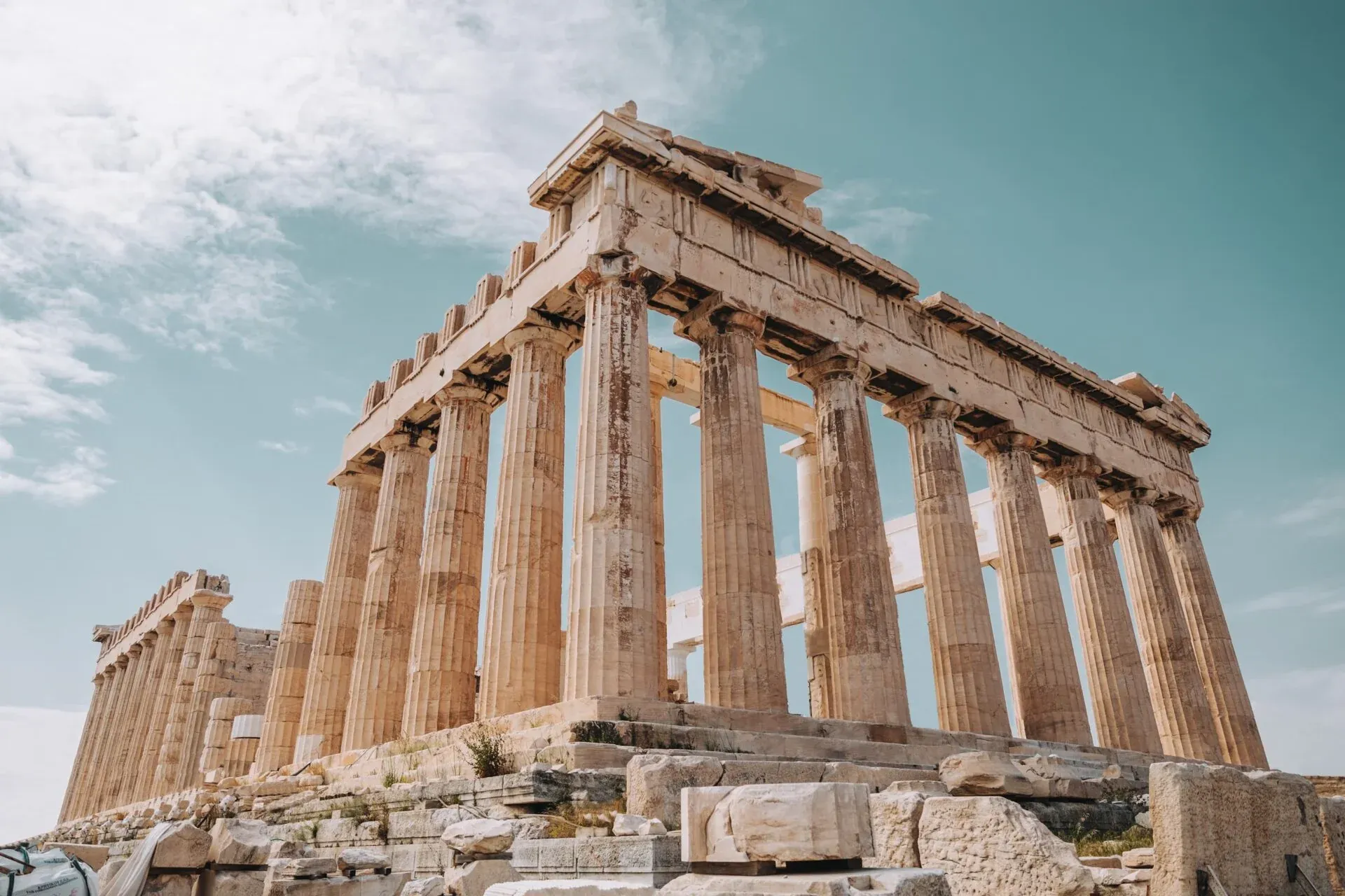 Vista del templo Partenón en la Acrópolis de Atenas, mostrando columnas dóricas bajo un cielo parcialmente nublado.