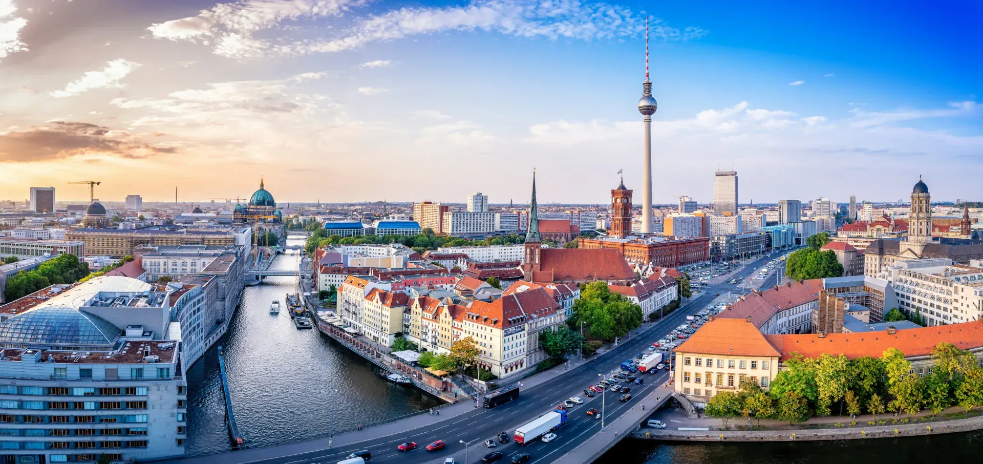 Panoramablick auf das Berliner Stadtzentrum mit dem Fernsehturm, dem Berliner Dom und der Spree bei Sonnenuntergang.