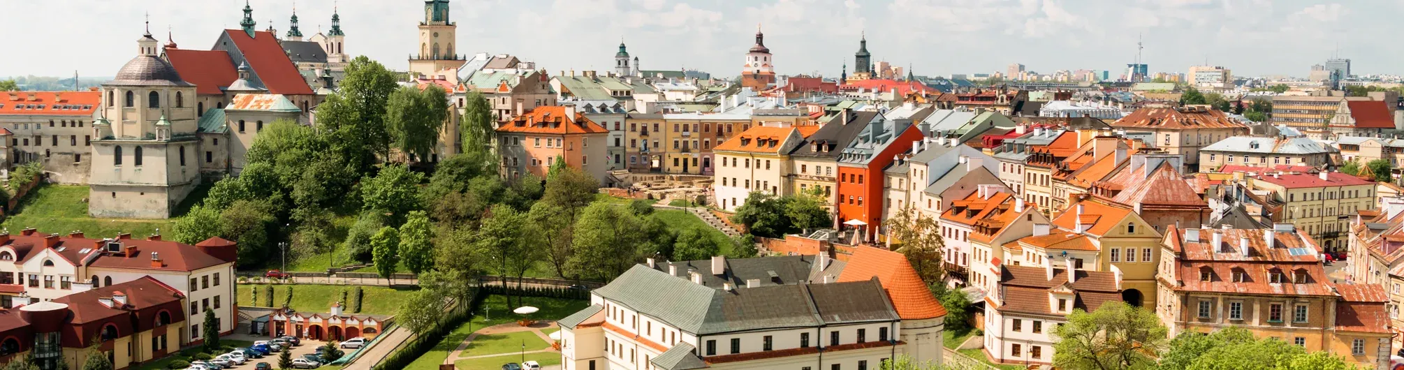 Panoramablick auf die Altstadt von Lublin mit historischen Gebäuden, vielfältigen Dächern, grünen Bäumen und mehreren Kirchtü