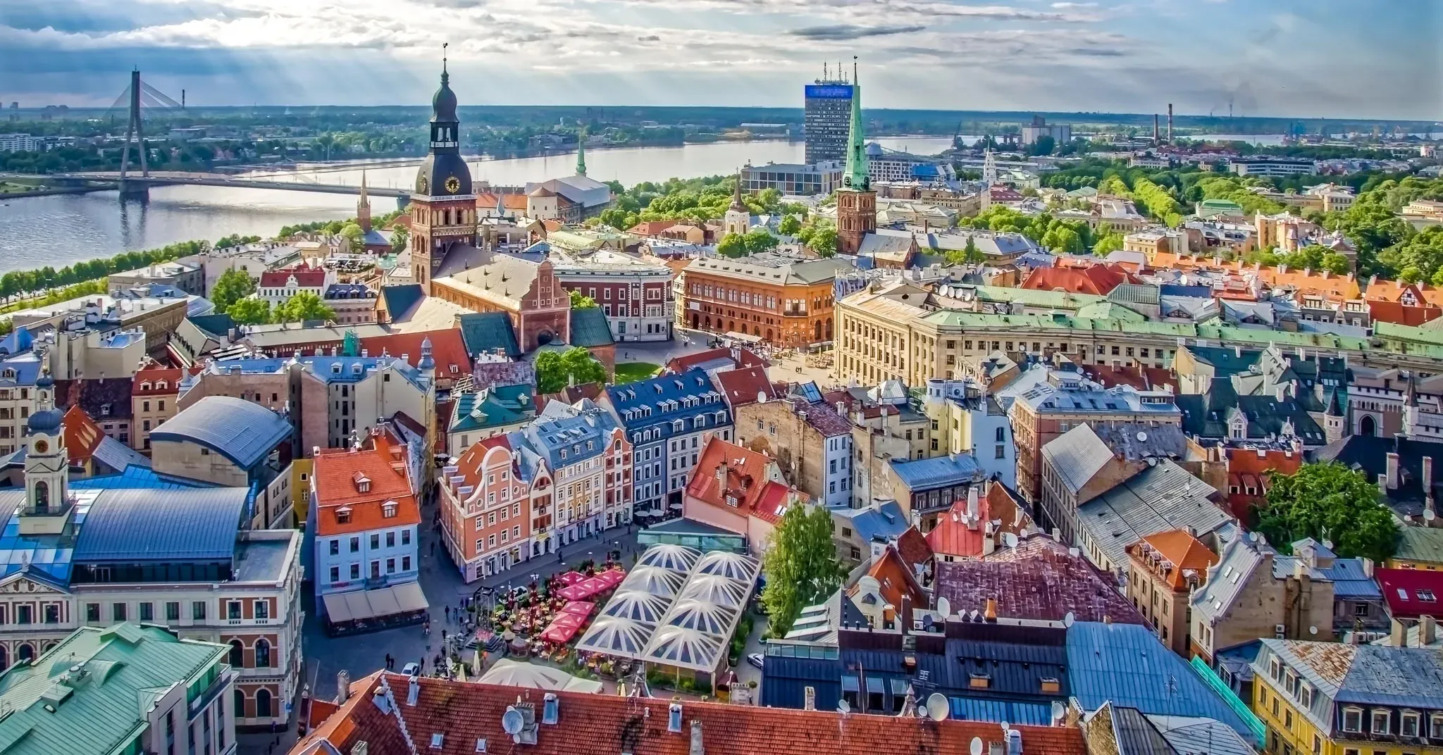 Panoramic aerial view of Riga Old Town with colorful rooftops, historic churches, and the Daugava River.