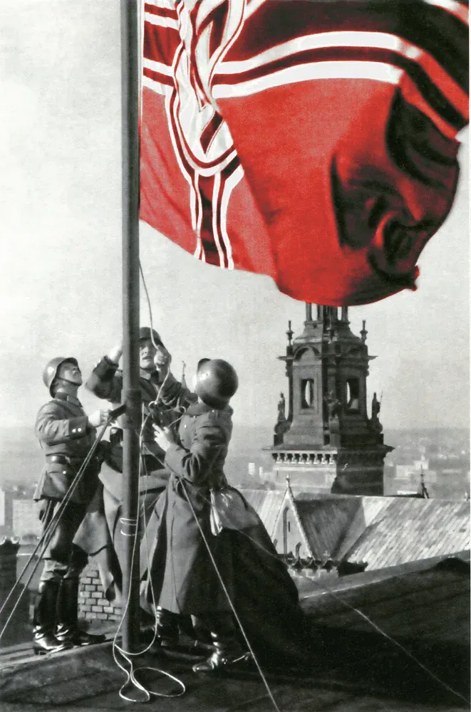 Soldaten hissen eine Flagge auf einem Dach in Krakau.