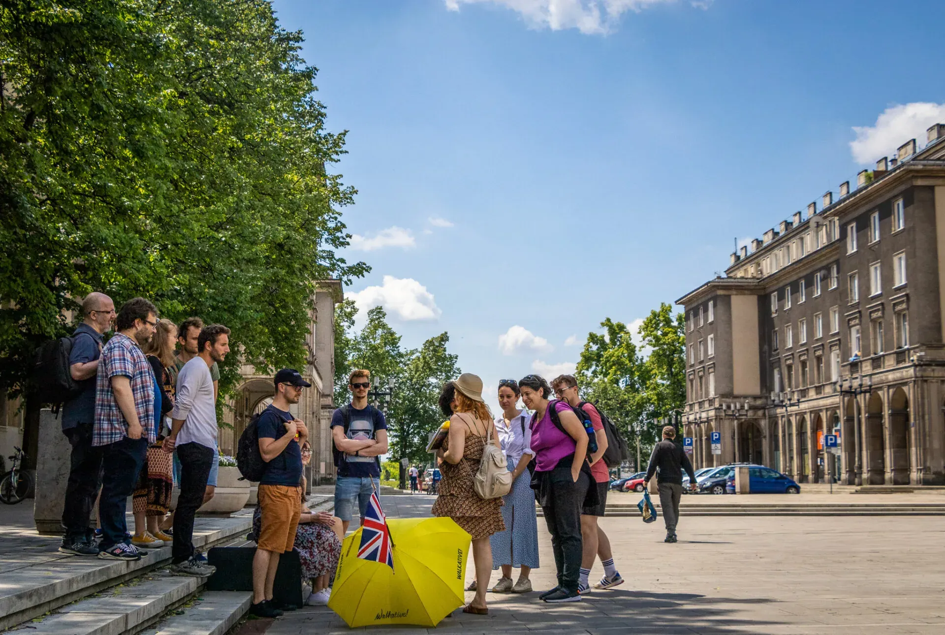 Eine geführte Touristengruppe erkundet einen sonnigen Stadtplatz in Krakau, Polen.