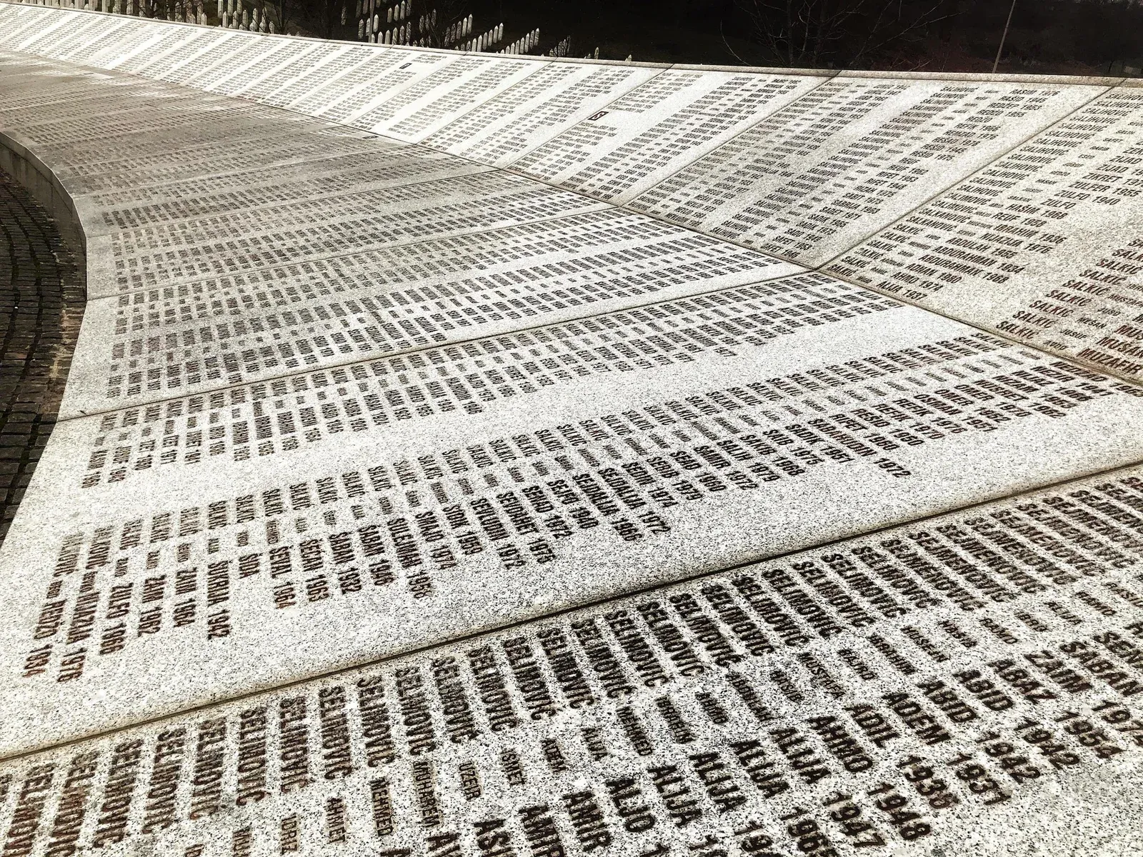 A curved memorial wall inscribed with numerous names and dates.