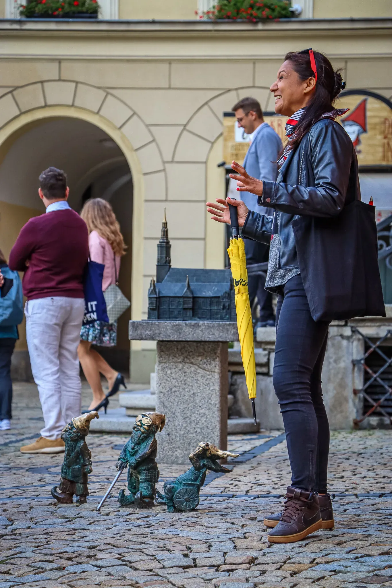 Przewodnik wrocławski wskazuje na krasnale grupie turystów.