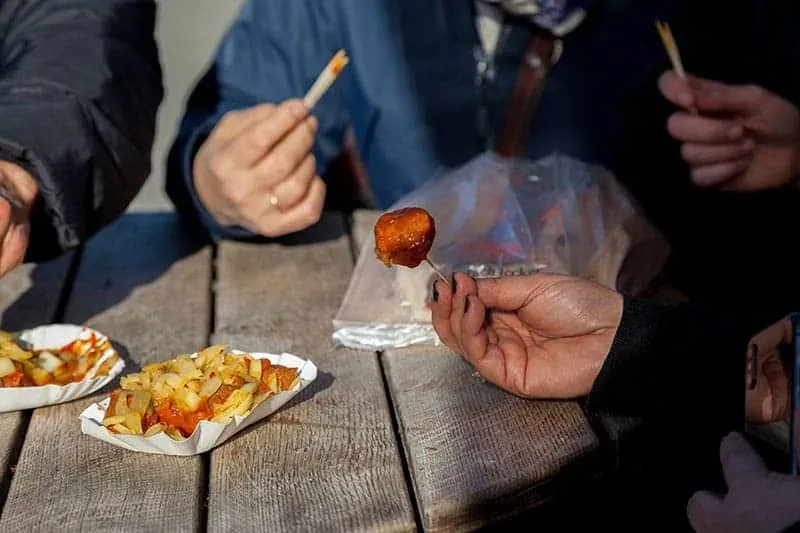 Touristen genießen Currywurst in Berlin.