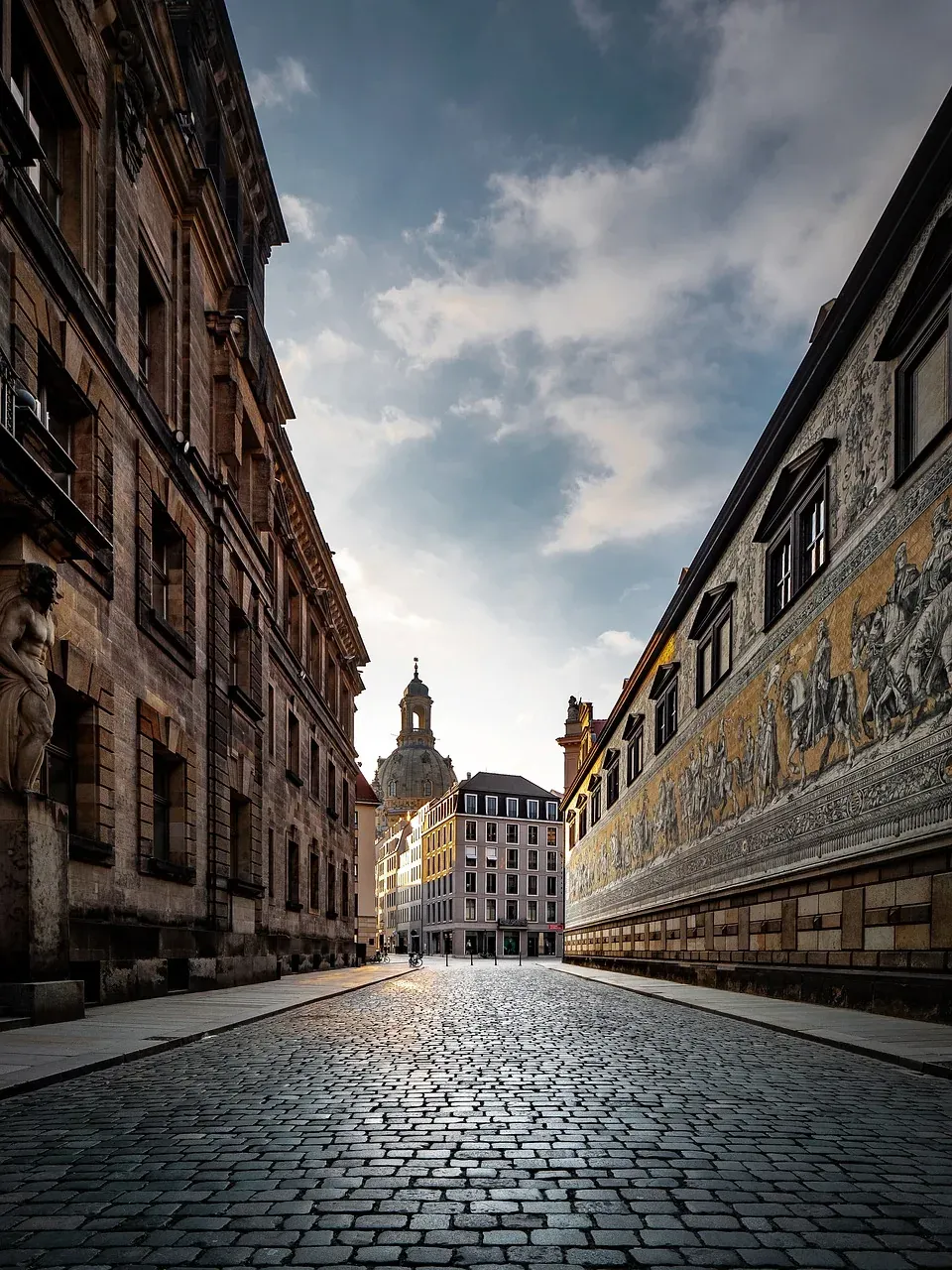 Calle empedrada en Dresde, Alemania, con edificios históricos y un fresco.