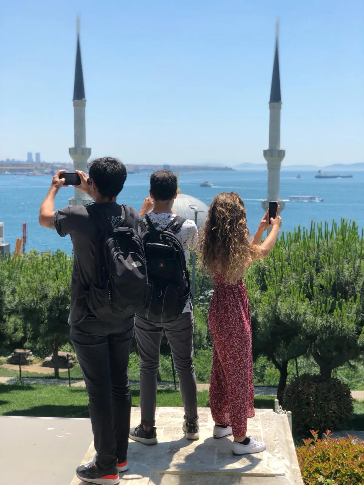 Tourists taking photos of a beautiful mosque and the Bosphorus in Istanbul.