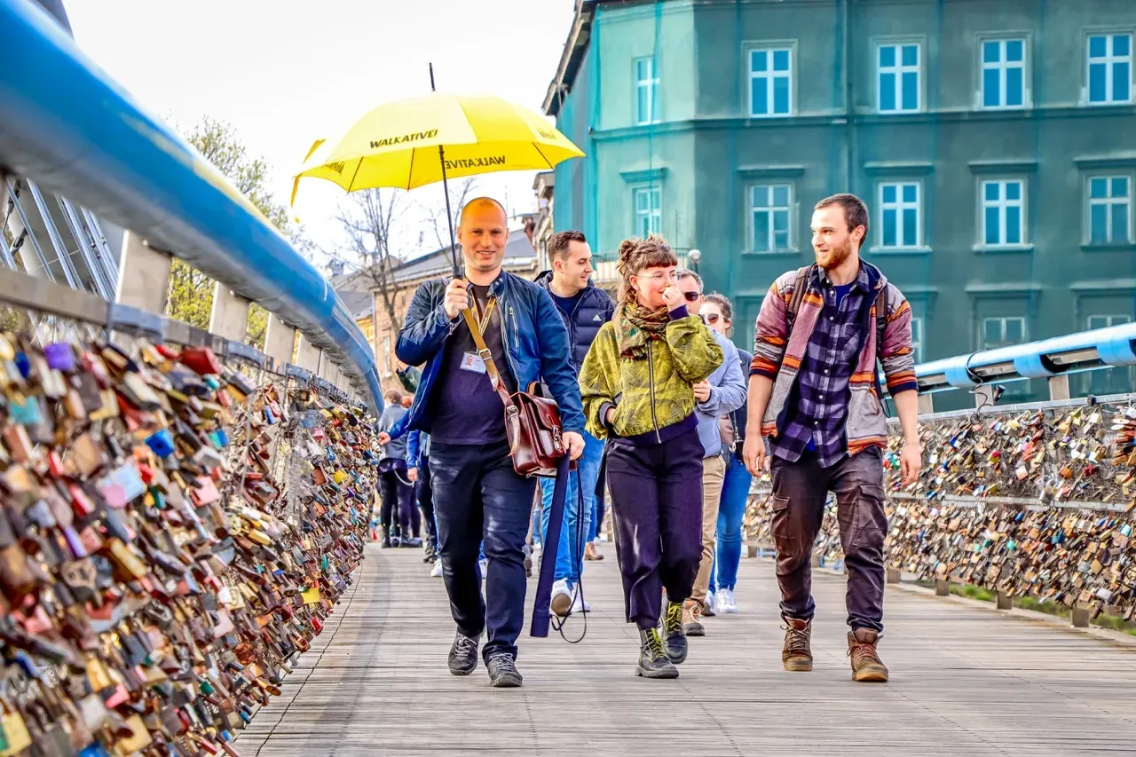 Un grupo de la excursión Walkative explora Cracovia, Polonia, caminando por un puente cubierto de candados de amor.