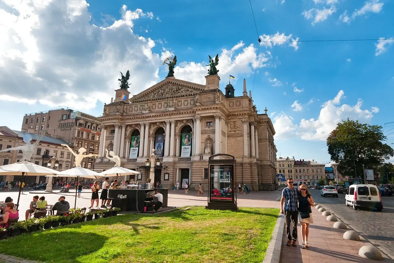 Touristen genießen den sonnigen Platz vor dem prächtigen Opernhaus in Lviv, Ukraine.