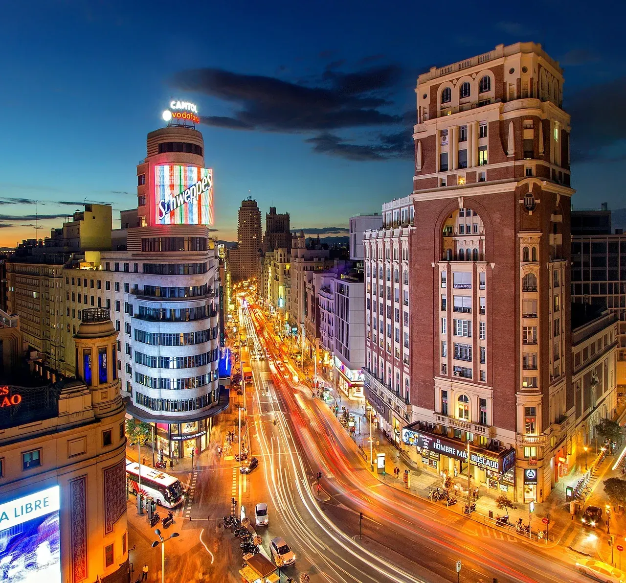 Vista nocturna de la Gran Vía de Madrid, mostrando su vibrante arquitectura y la bulliciosa vida callejera.