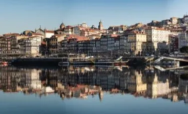 Panoramic view of Porto's Ribeira district reflected in the Douro River.