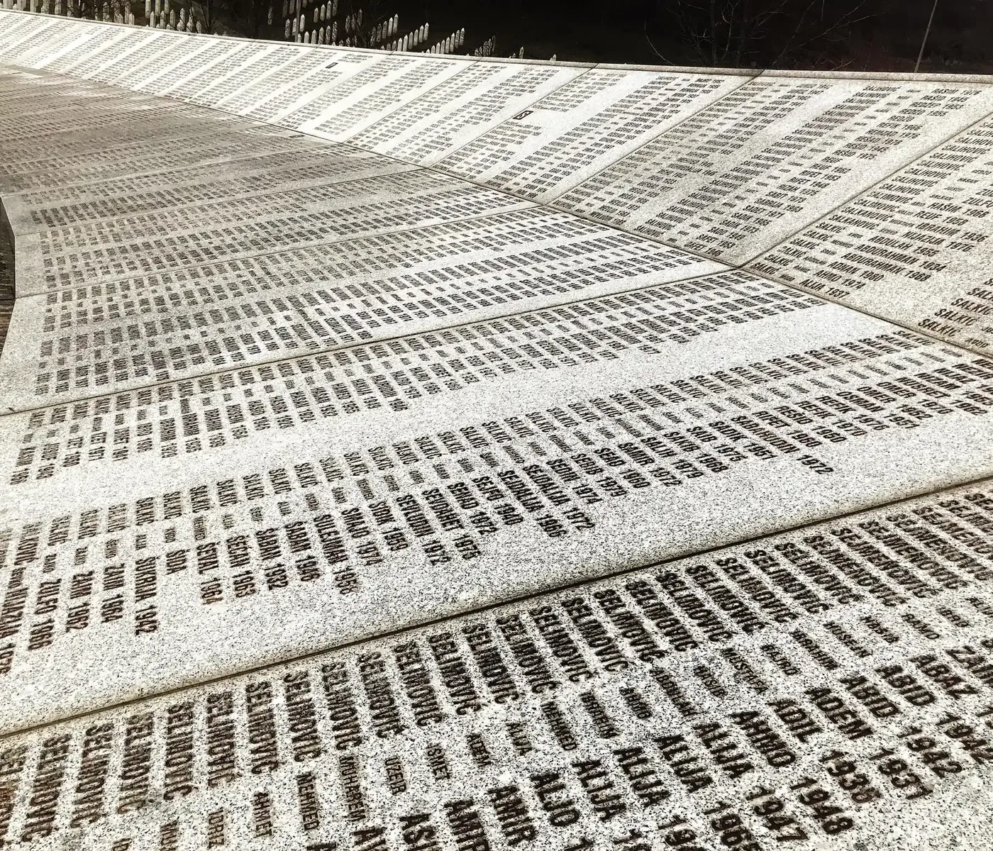 A curved memorial wall inscribed with numerous names and dates.