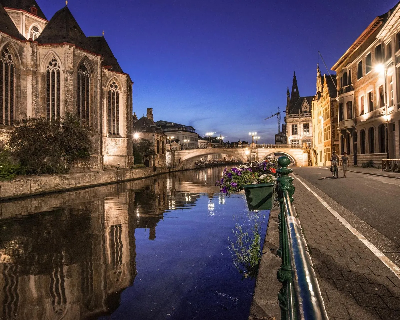 Ghent's charming canal at night, reflecting historic buildings.