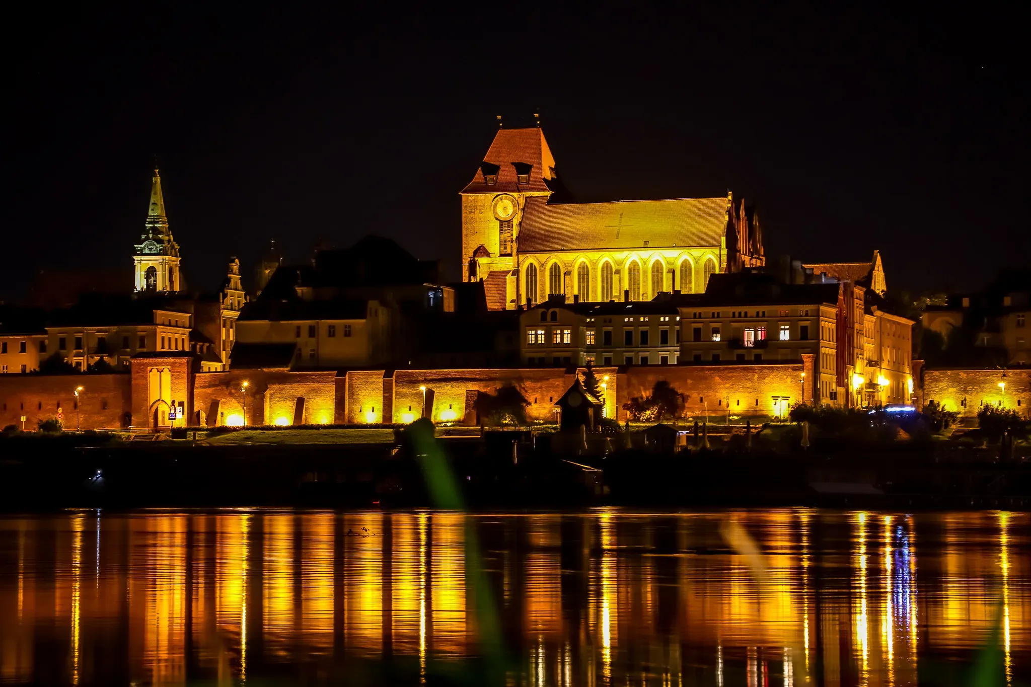 Vista nocturna del casco antiguo de Toruń reflejada en el río Vístula.
