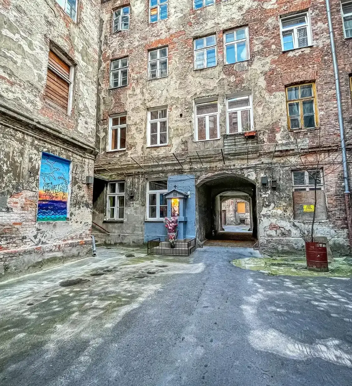 Entdecken Sie einen versteckten Warschauer Innenhof mit alten Backsteingebäuden, Street Art und einem kleinen Schrein.